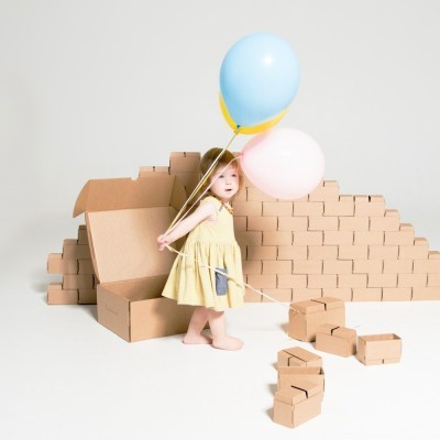 Criança com balões entre caixas de cartão marrons