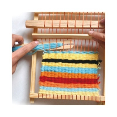 Tear artesanal de madeira com fios coloridos e mãos a trabalhar