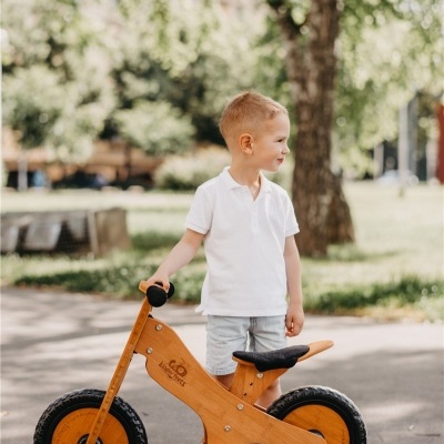 Criança com bicicleta de equilíbrio de madeira em parque