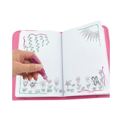 Pessoa a colorir desenhos de flores num caderno aberto com marcador rosa glitter e capa rosa.