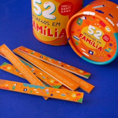 Jogo '52 Desafios em Família' com embalagem cilíndrica amarela e tiras de papel laranja