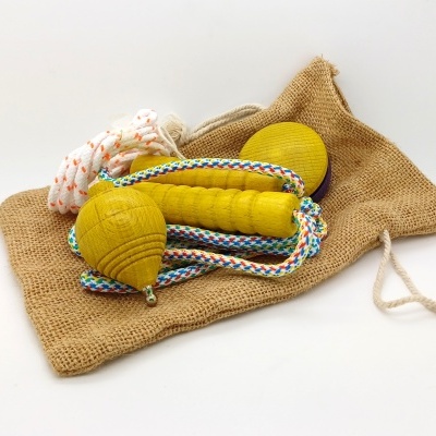 Brinquedos de madeira amarelos com corda colorida sobre bolsa de tecido saco