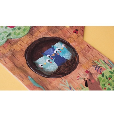 Ilustração de três corujas azuis num ninho em árvore com elementos naturais ao redor.