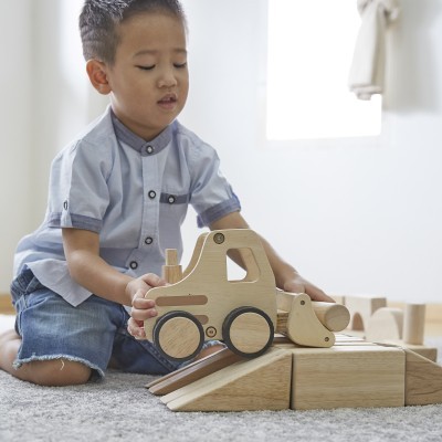 Criança a brincar com brinquedo de camião de construção de madeira