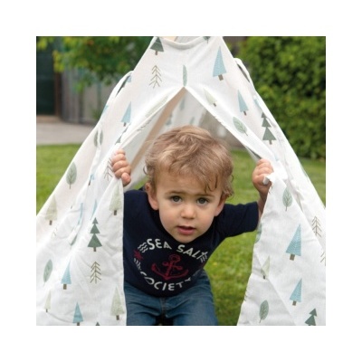 Criança a sair de uma tenda infantil branca com padrão de árvores verdes e azuis, em relva.