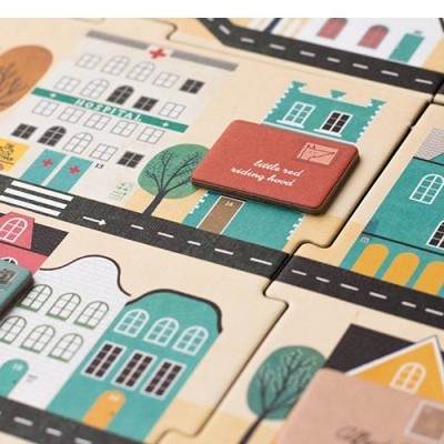 Jogo de tabuleiro com peças coloridas representando casas, ruas e placas com texto