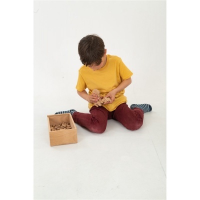Criança sentada no chão a brincar com peças de madeira dentro de caixa