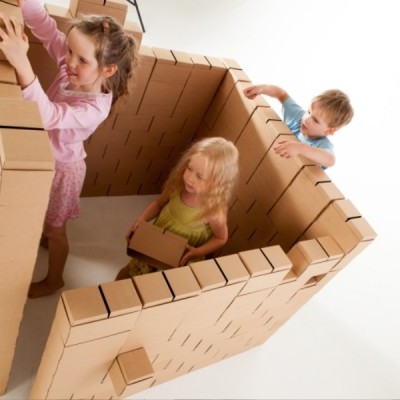 Crianças a brincar dentro de uma estrutura feita de caixas de cartão.