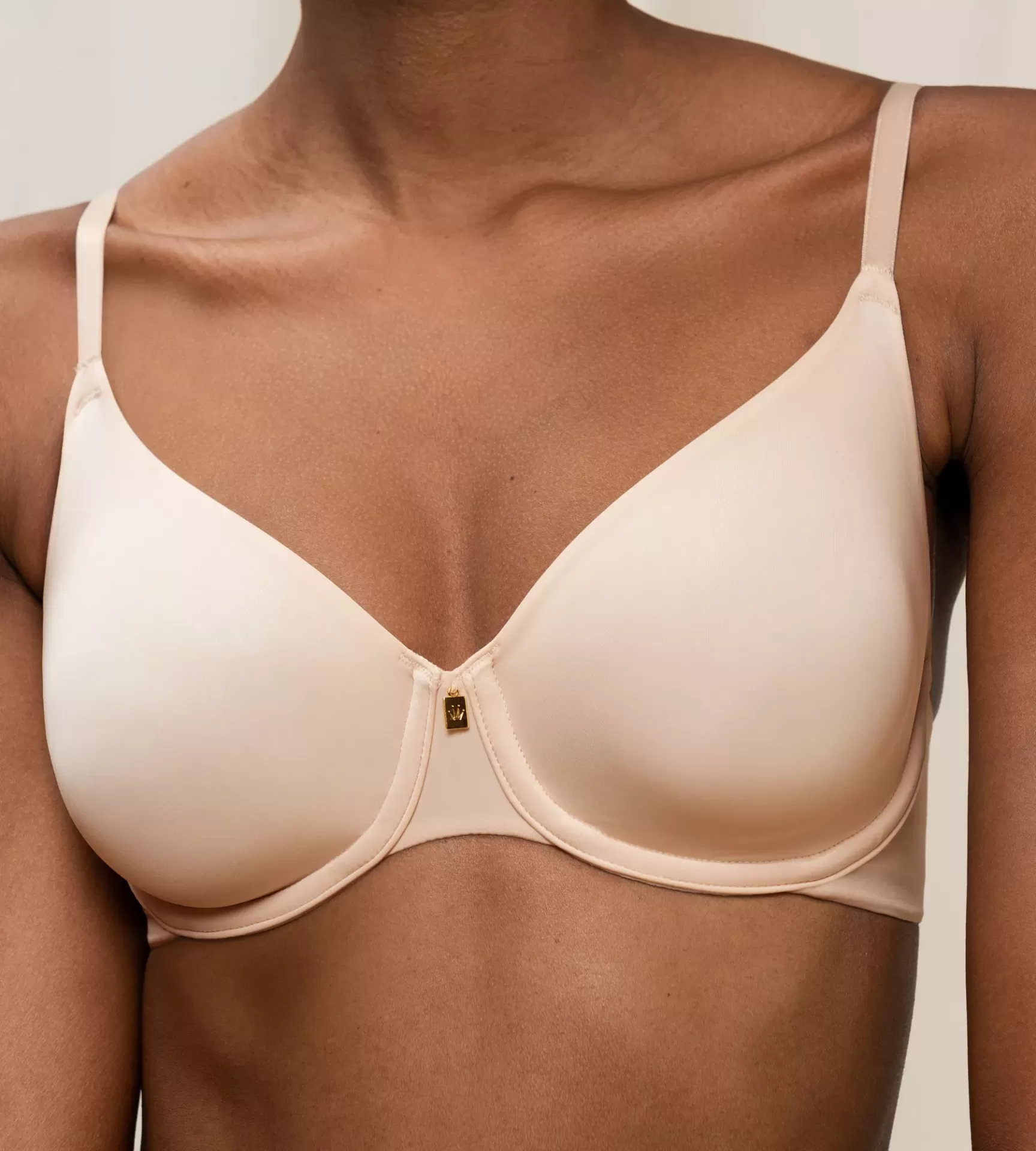 Soutien bege claro com aro e alças finas, detalhe dourado no centro