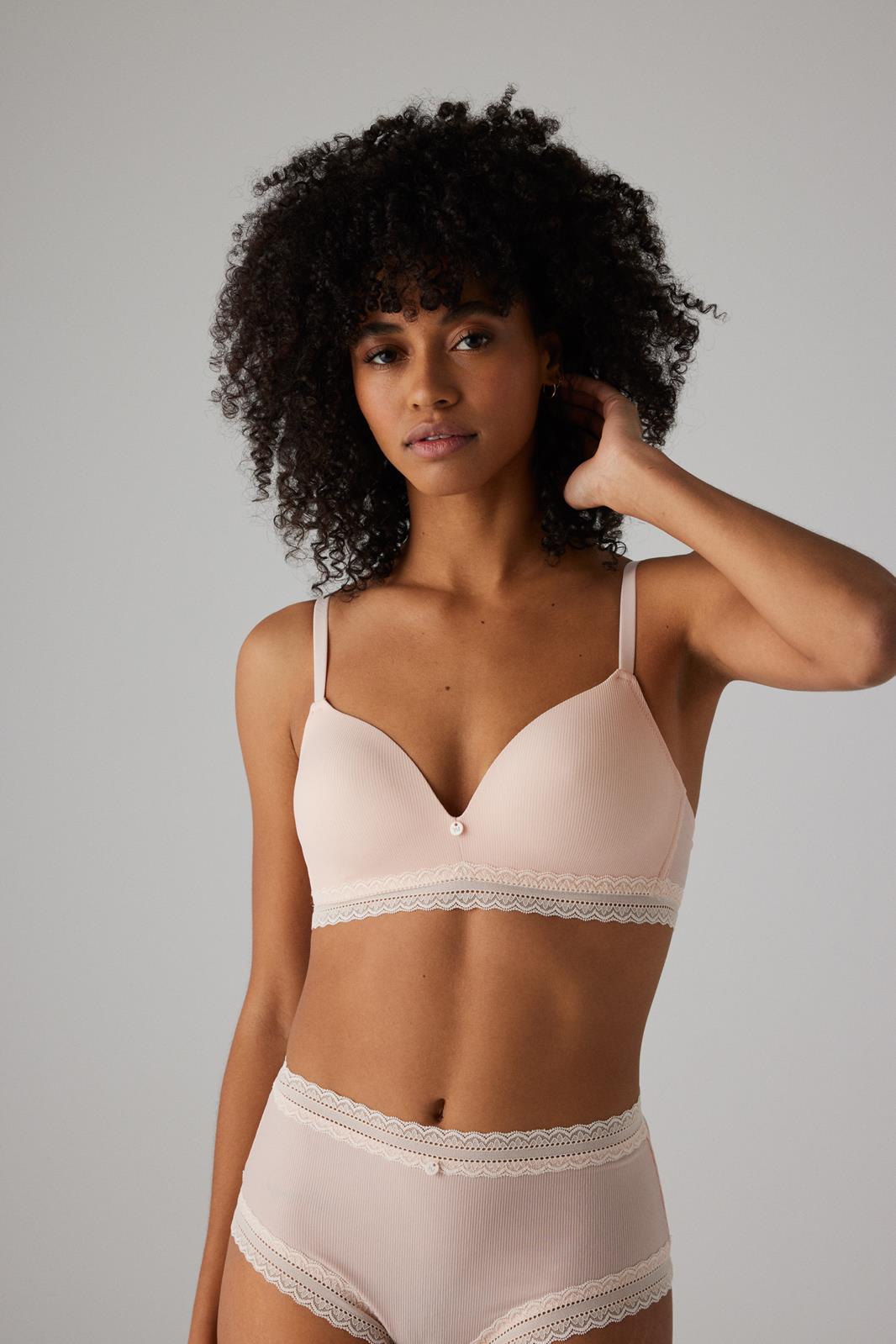 Conjunto de lingerie rosa claro em mulher com fundo cinza