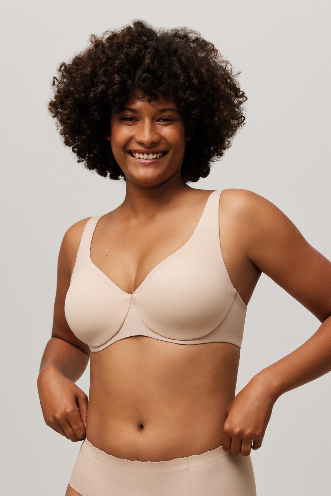 Soutien bege claro de tecido liso com alças largas, usado com cuecas altas, sem padrões, em fundo cinza claro