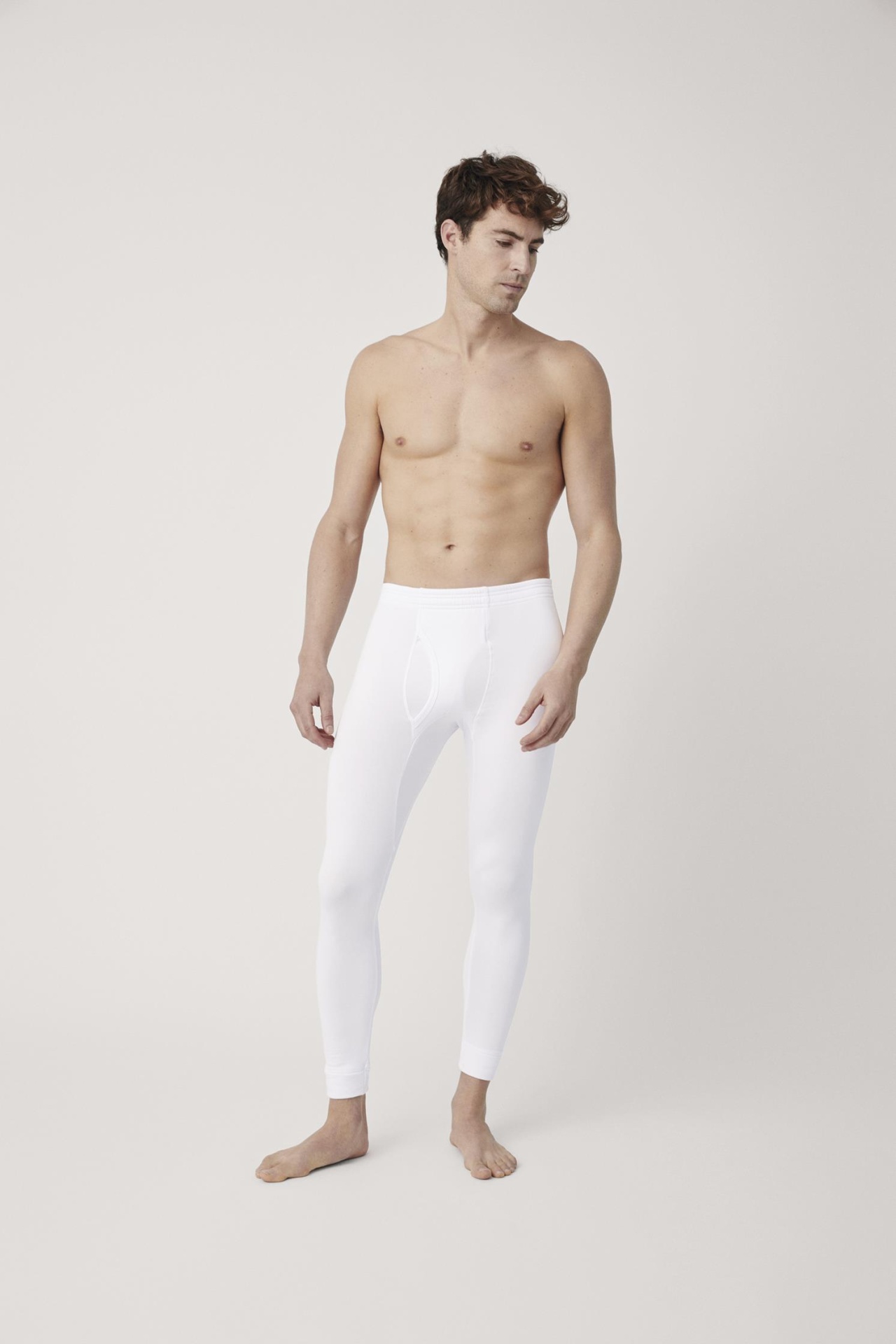Homem de boxers compridos brancos justos em fundo neutro