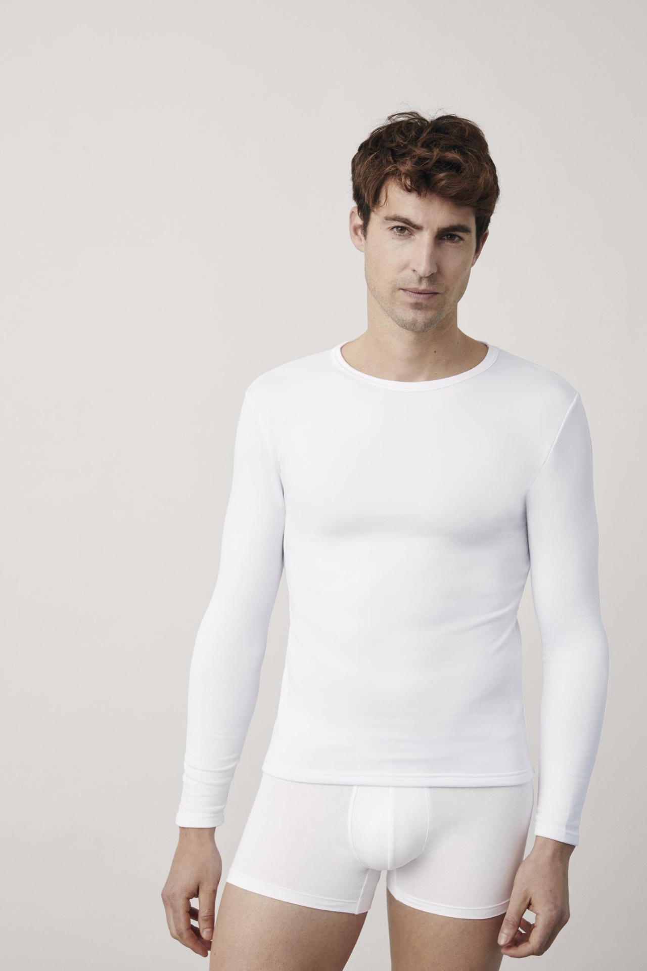 Homem com roupa interior branca, camisola de manga comprida e cuecas boxer.