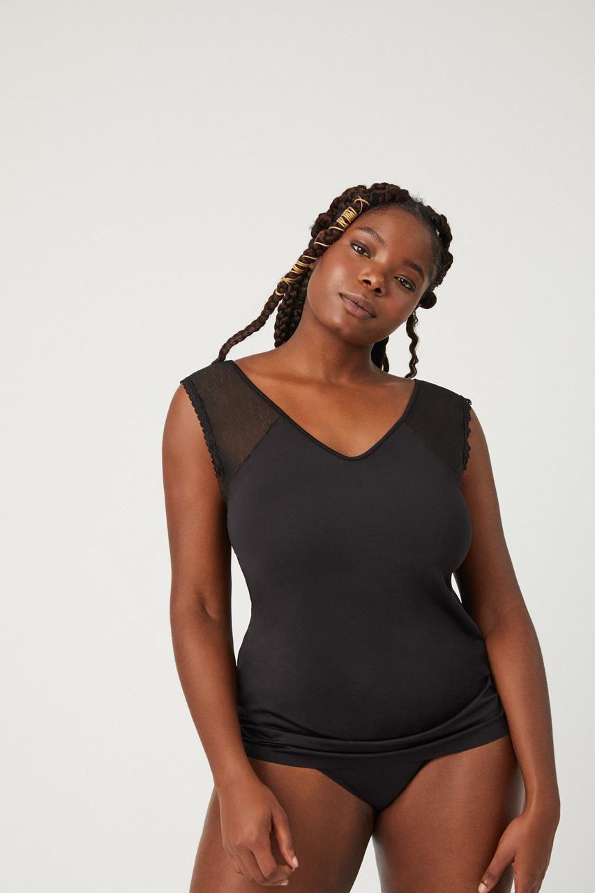 Mulher com roupa interior preta com detalhe em tule nos ombros em fundo branco