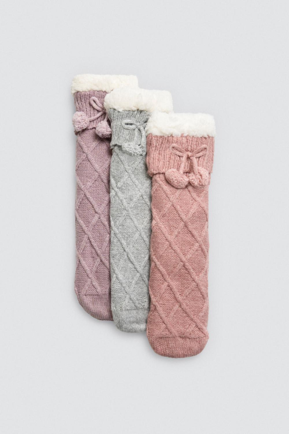Três meias compridas de malha rosa, cinza e rosa claro com acabamento felpudo branco e laços com pompons