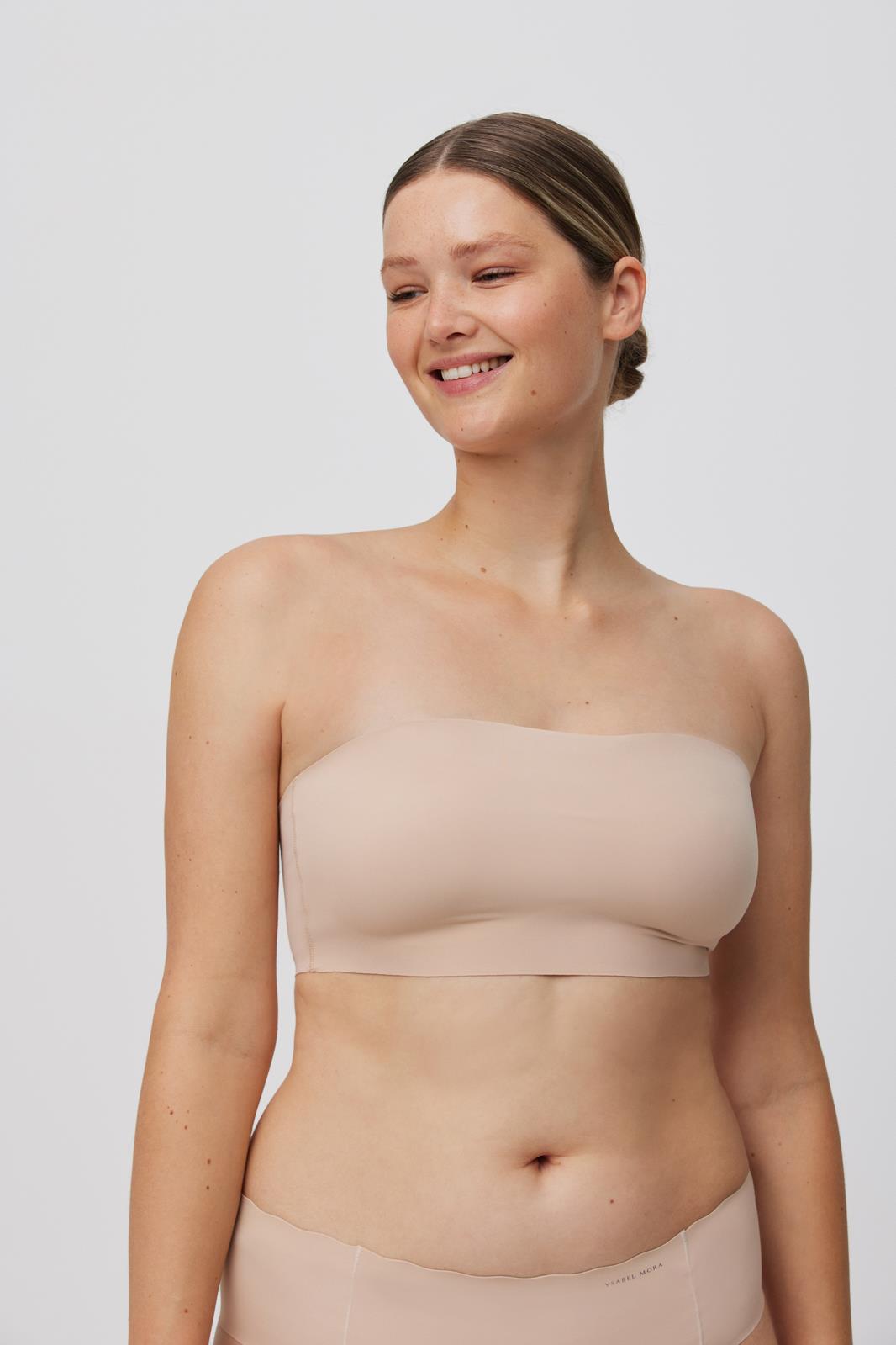 Mulher a usar top bandeau e cuecas cor de pele sobre fundo branco