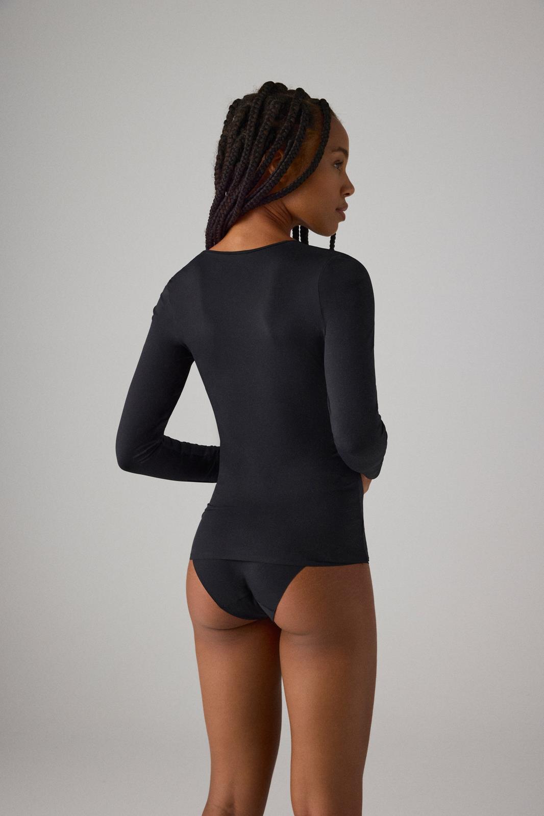 Mulher de costas com camisola preta de manga comprida e cuecas tipo tanga pretas