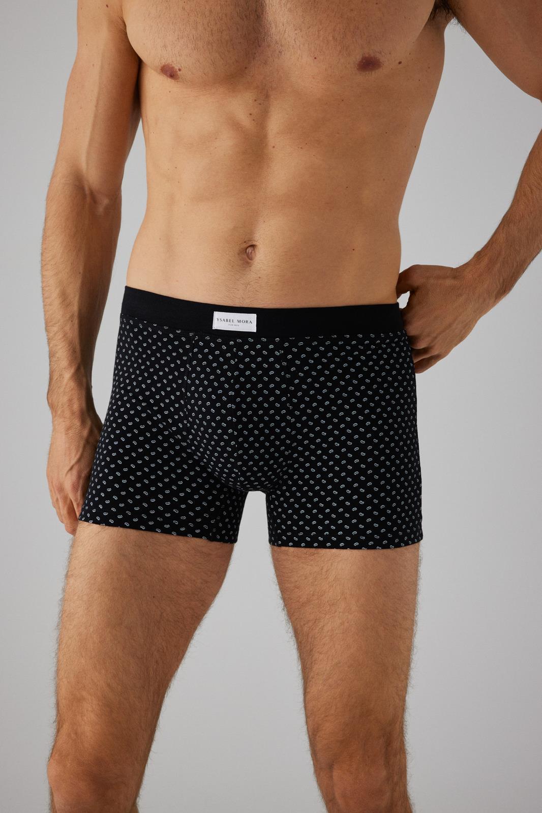 Cuecas boxer pretas com padrões brancos e etiqueta PAUL JONES na cintura, usadas por modelo masculino sem camisa