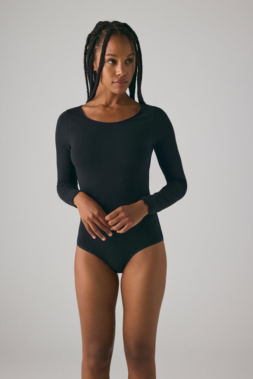 Body feminino preto de manga comprida com decote redondo em fundo cinzento