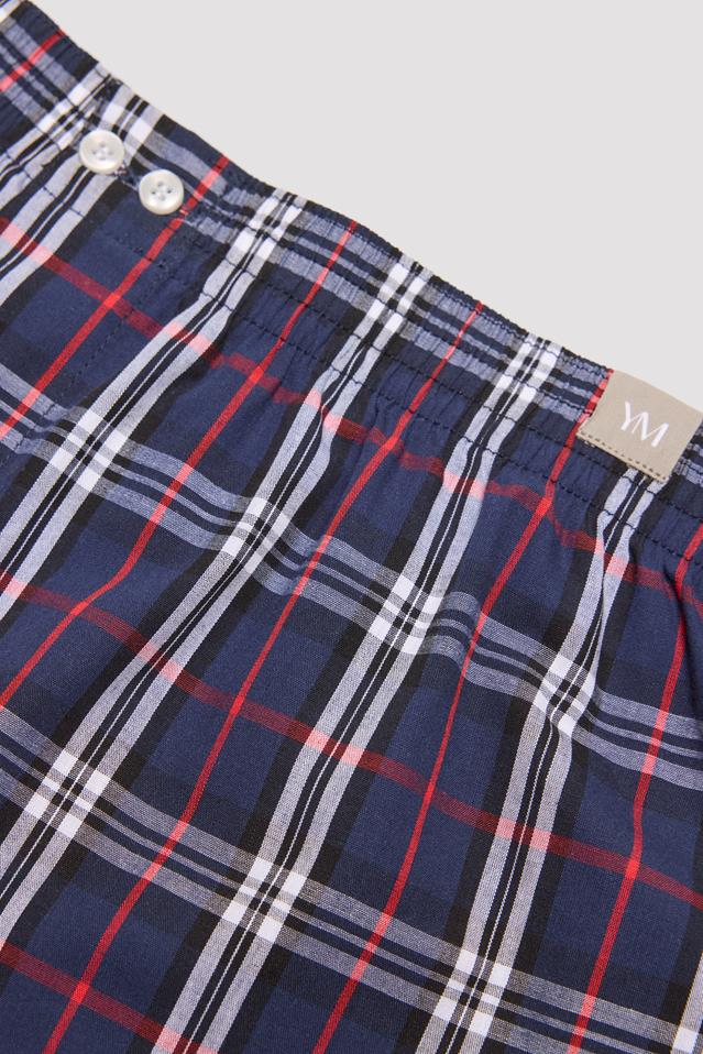 Peça de vestuário xadrez azul, vermelho, branco e preto com botões brancos na cintura elástica