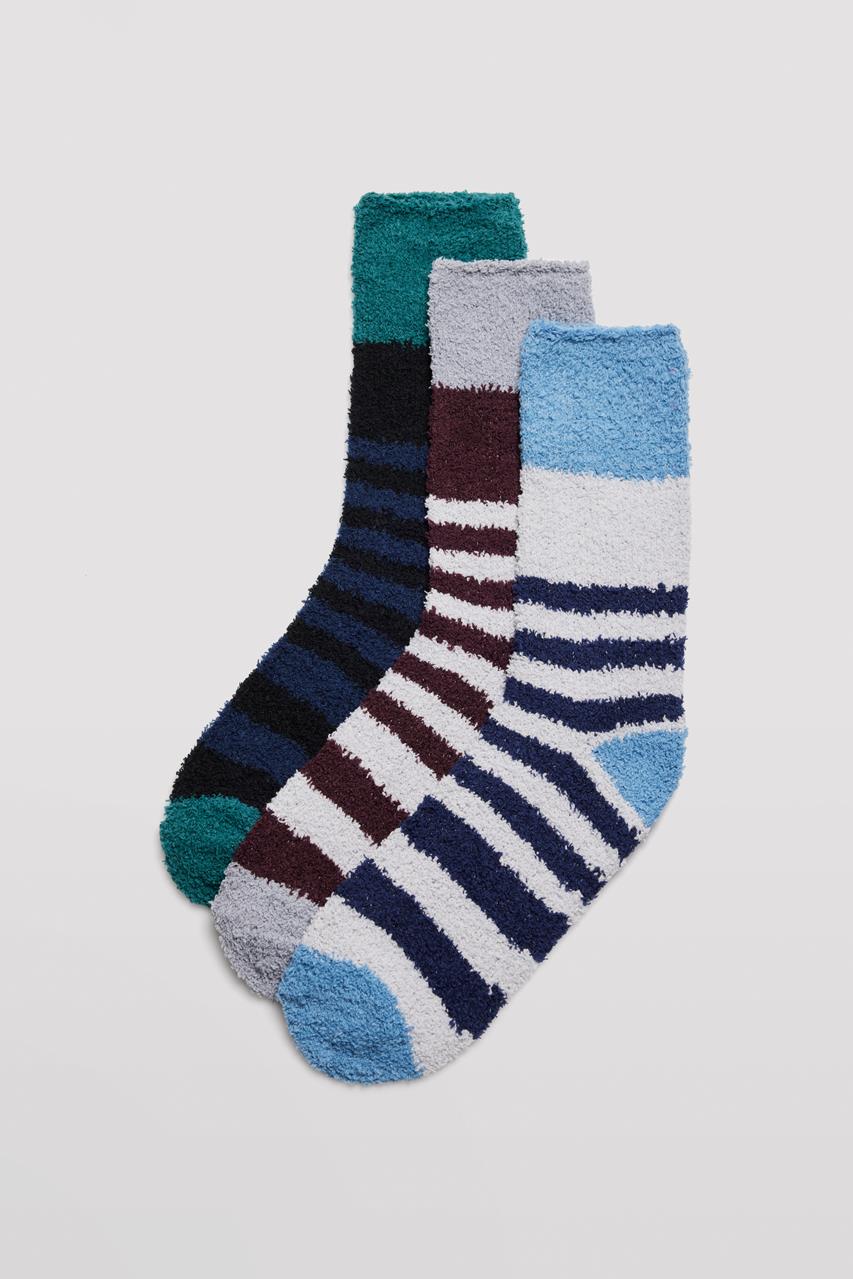 Três pares de meias ás riscas, materiais felpudos, em várias cores.