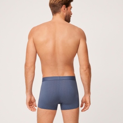 Homem de costas com cuecas boxer azuis com padrão de pequenos pontos brancos