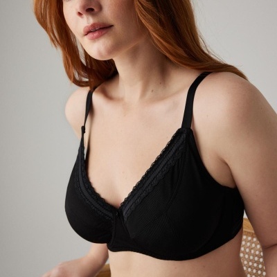 Mulher com soutien preto de algodão com renda e alças ajustáveis sentada numa cadeira
