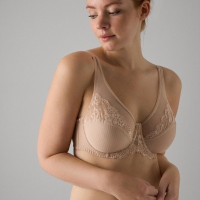 Mulher com lingerie bege com renda e riscas em fundo cinza