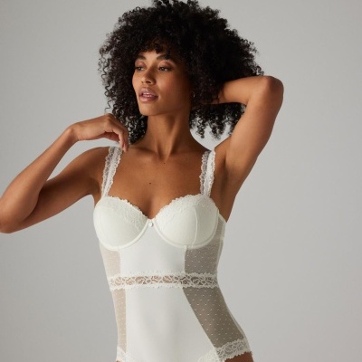 Body feminino branco com detalhes em renda e tule de pontos sobre fundo cinza claro