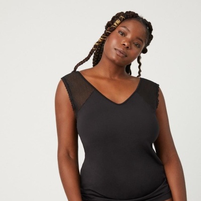 Mulher com roupa interior preta com detalhe em tule nos ombros em fundo branco