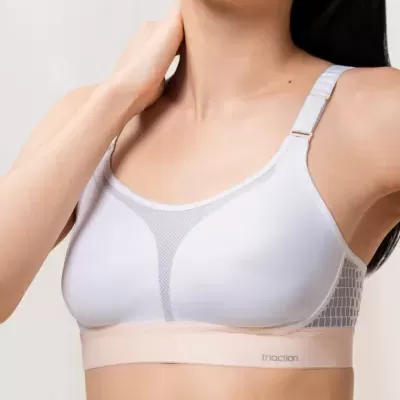 Soutien desportivo branco e bege com tirantes ajustáveis e detalhe em malha.