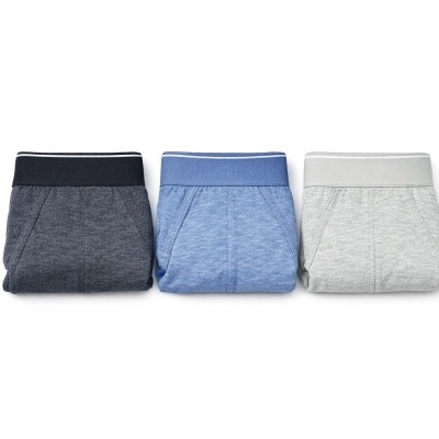 Três calças de ganga dobradas em tons cinza escuro, azul e cinza claro