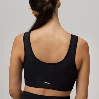 Top desportivo preto canelado visto das costas