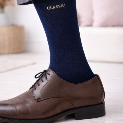 Meia azul escura com palavra CLASSIC usada com sapato castanho de couro e calças cinzentas