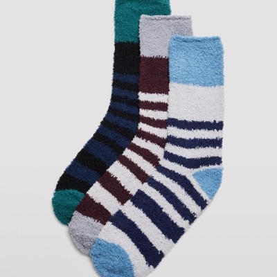 Três pares de meias ás riscas, materiais felpudos, em várias cores.