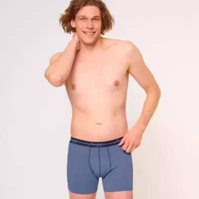 Homem vestindo boxers azuis com cós azul escuro com texto em fundo claro.