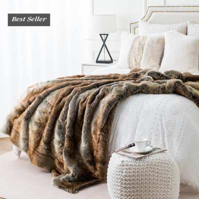 Manta de pelo sintético em cama branca com almofadas claras e mesa de cabeceira