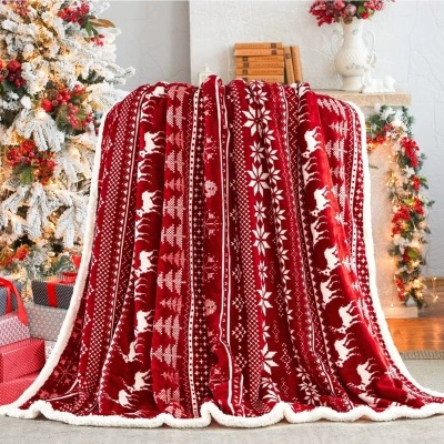 Manta vermelha natalícia com padrão de renas e flocos de neve, num ambiente decorado para o Natal.