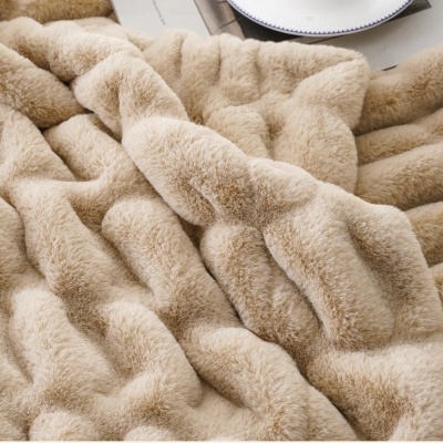 Manta felpuda bege claro com textura ondulada, parte de prato branco ao fundo