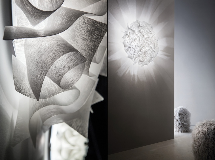 VELI COUTURE wall Candeeiro decorativo branco com pétalas translúcidas e sombras na parede, pufes felpudos cinza claro ao fundo