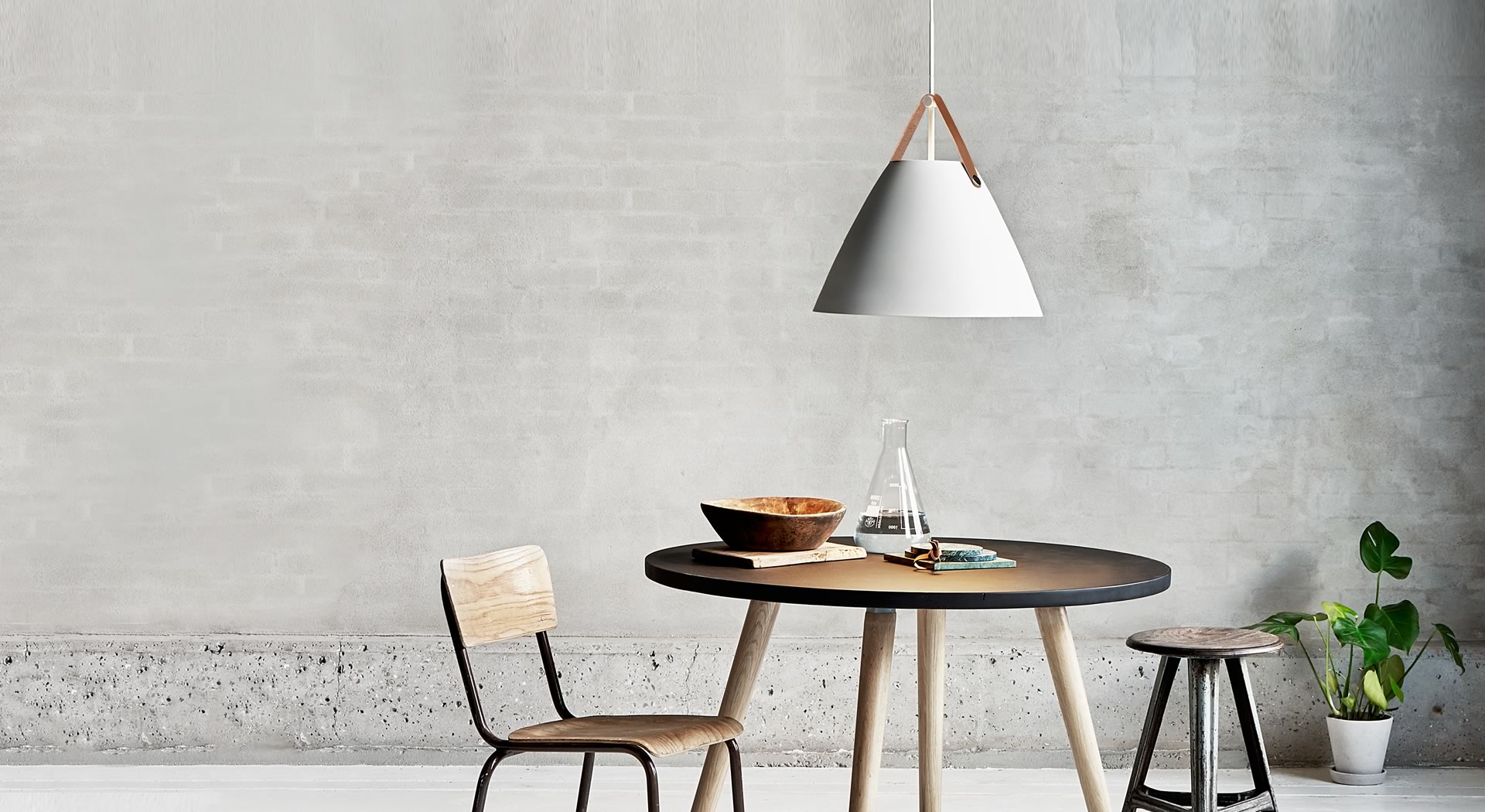 STRAP 27 | 36 | 48 Sala minimalista com mesa redonda preta, cadeira de madeira, banco escuro, lâmpada pendente e plantas em vasos.