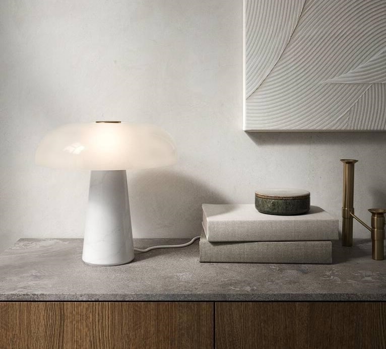 GLOSSY Candeeiro de mesa em mármore branco com cúpula opaca junto a livros e castiçais sobre aparador