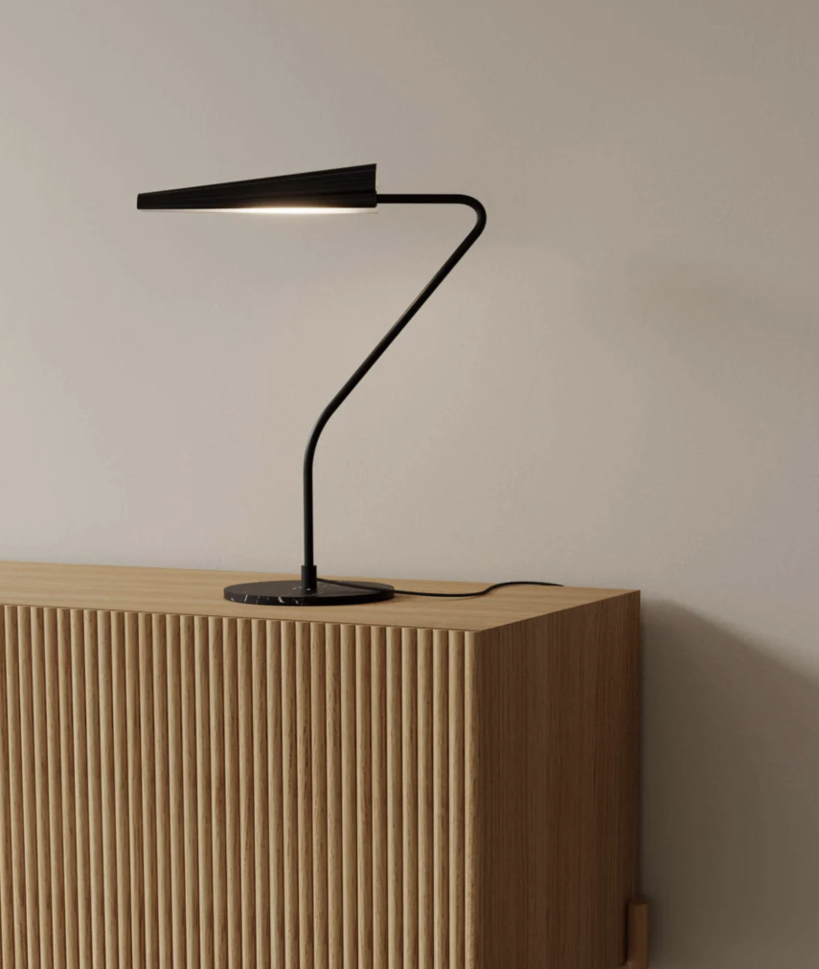 BION mesa Lâmpada de mesa preta sobre móvel de madeira clara com textura de linhas verticais