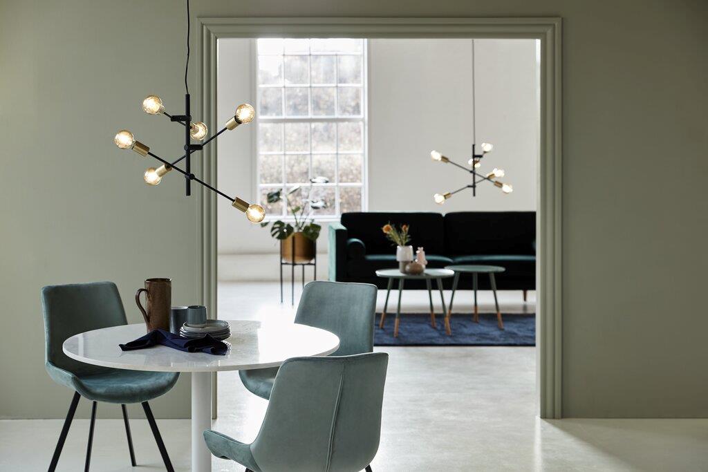 JOSEFINE L Sala moderna com mesa redonda branca e cadeiras cinza-azuis, luzes suspensas, sofá preto e janelas grandes
