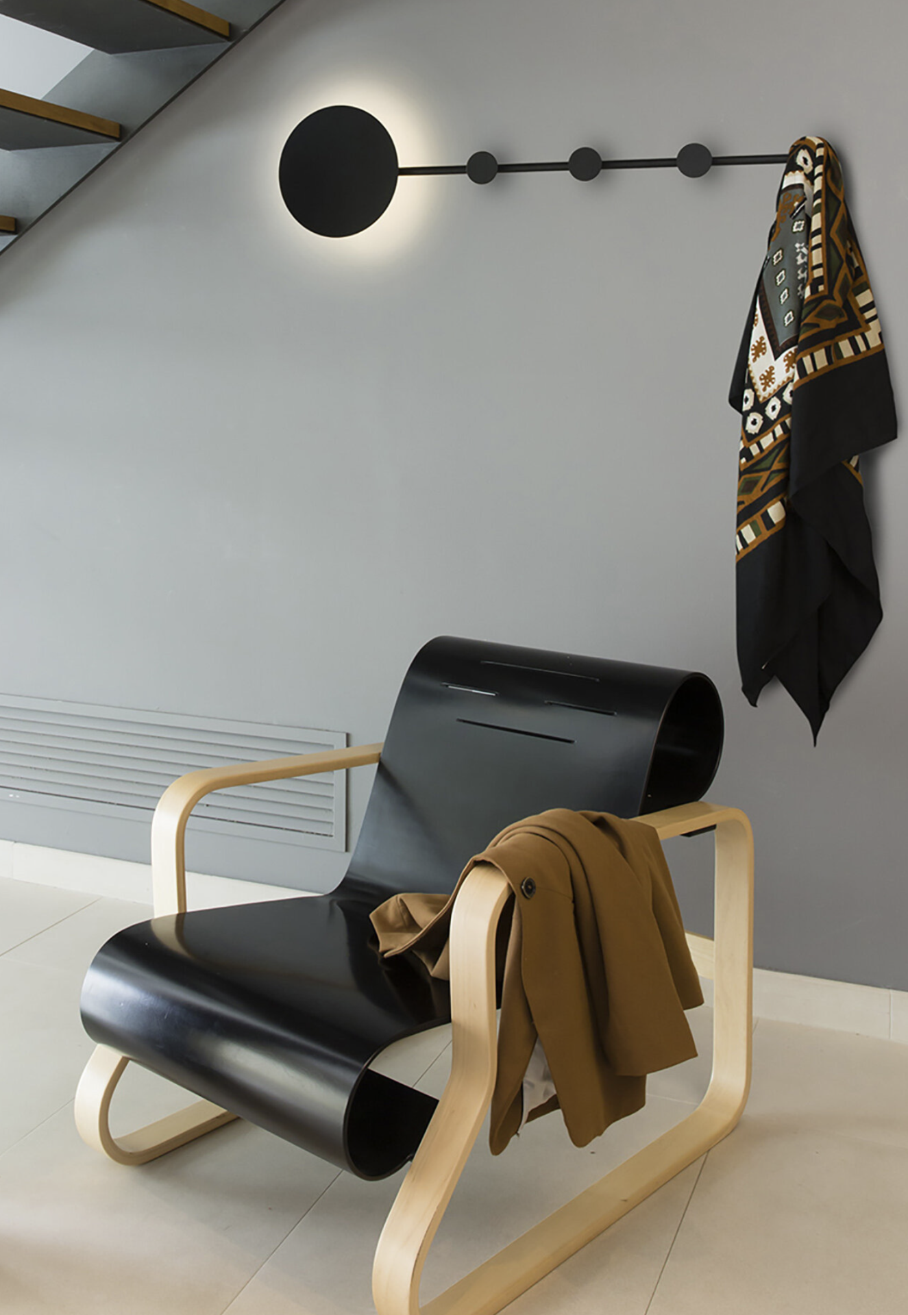 HAN LED Cadeira moderna em madeira clara e couro preto com casaco castanho em ambiente minimalista cinza.