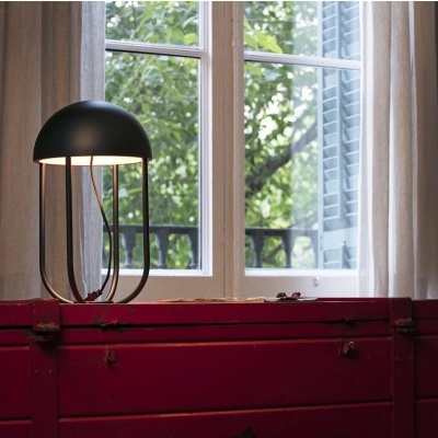 Abajur preto sobre caixa vermelha perto de janela com cortinas