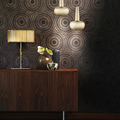 Aparelho de mobiliário de madeira escura com abajur dourado e vasos sobre ele, contra parede com padrão circular preto e dourado