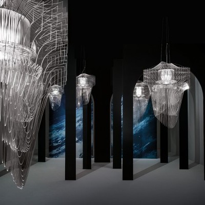 Esculturas suspensas com fios brancos em postes pretos num ambiente escuro