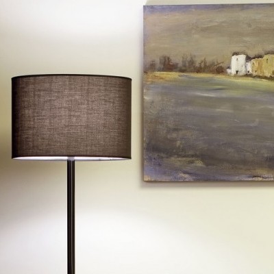 Candeeiro de pé com abajur cinzento junto a parede branca e pintura de paisagem