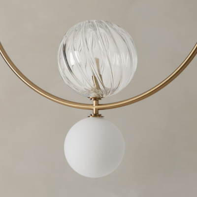 Lâmpada suspensa com estrutura circular dourada e duas esferas de vidro, uma transparente com textura em espiral e outra branca opaca